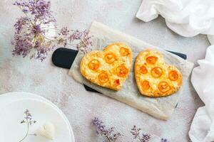 Two heart shaped pizzas on paper on a set table for valentine's day celebration. Top view photo