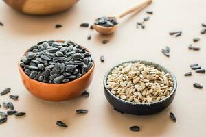 Choose between peeled and unpeeled sunflower seeds in bowls on the table. Natural source of vitamins and fat photo