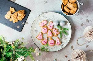 Freshly baked Christmas cookies with pink icing on a plate on a decorated table. Festive treat. Top view. photo