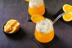 Dirty orange soda with whipped cream in glasses and orange slices on the table photo