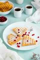 Heart shaped Belgian waffles with red berry and powdered sugar on a plate on the breakfast table. Valentine's Day. Vertical view photo