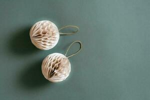 Two Christmas textured folded balls from craft paper on a green background. Copy space photo