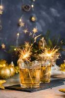 Burning sparklers in glasses with cocktails on the Christmas table. Gold palette. Vertical view photo