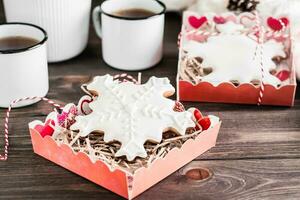 Gingerbread snowflakes with icing in open boxes and two mugs of tea on a wooden table. Christmas treat photo