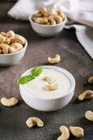 Vegan cashew sauce in bowl with basil on table for plant based diet vertical view photo