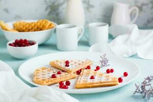 Heart shaped Belgian waffles with red berry and powdered sugar on a plate on the breakfast table. Valentine's Day photo