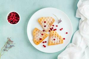 Heart shaped Belgian waffles with red berries and powdered sugar on a plate on the table. Valentine's Day. Top view. Copy space photo