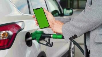 mujer usos un móvil solicitud en un teléfono inteligente a pagar para repostaje un coche. teléfono inteligente con un verde pantalla. croma llave video