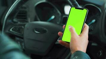 conductor utilizando un teléfono inteligente dentro el coche. chromakey teléfono inteligente con verde pantalla. auto navegación. Internet adiccion. automóvil seguro solicitud. video