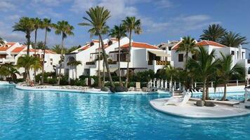 Schwimmen Schwimmbad im direkt am Strand tropisch Hotel Resort mit Palme Bäume zum Strand Ferien Urlaub, Luxus Ziel. Teneriffa, Kanarienvogel Inseln, Spanien. schleppend Bewegung video