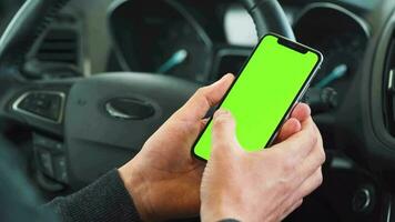 bestuurder gebruik makend van een smartphone binnen de auto. Chroma sleutel smartphone met groen scherm. auto navigatie. internet verslaving. auto- verzekering sollicitatie. video