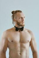 Portrait of handsome caucasian athletic young man topless in leather bow tie. Fitness, bodybilding photo