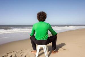 Back view of a man sitting on a beach. photo