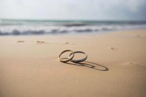 Two wedding rings in the sand on the background of a beach and sea. photo