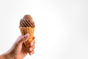 Hand holding delicious chocolate ice cream in a crispy waffle cone with copy space. photo