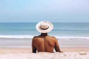 espalda ver de un hombre vistiendo un sombrero sentado en un playa. ai generado foto