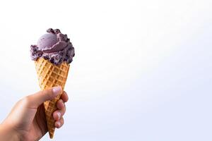 Hand holding delicious blueberry ice cream in a crispy waffle cone with copy space. photo