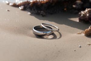 dos Boda anillos en el arena en el antecedentes de un playa y mar. ai generado foto