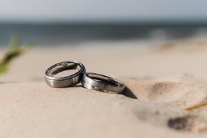 dos Boda anillos en el arena en el antecedentes de un playa y mar. ai generado foto