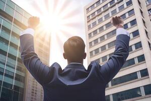 Successful businessman raising hand and expressing positivity while standing against skyscrapers background. photo