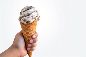 Hand holding delicious cookies and cream ice cream in a crispy waffle cone with copy space. photo