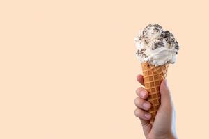 Hand holding delicious cookies and cream ice cream in a crispy waffle cone with copy space. photo