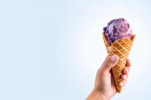 Hand holding delicious blueberry ice cream in a crispy waffle cone with copy space. photo