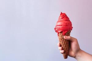 Hand holding delicious red velvet ice cream in a crispy waffle cone with copy space. photo