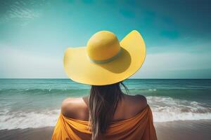 Back view of a woman wearing a hat sitting on a beach. photo