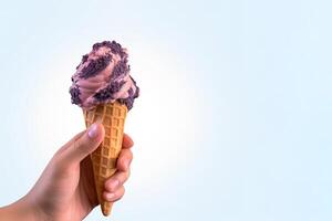 Hand holding delicious blueberry ice cream in a crispy waffle cone with copy space. photo