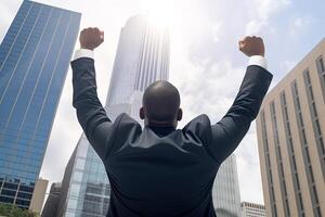 Successful businessman raising hand and expressing positivity while standing against skyscrapers background. photo