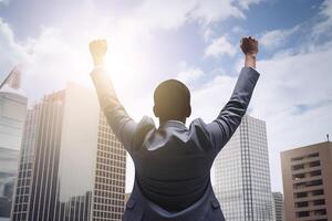 Successful businessman raising hand and expressing positivity while standing against skyscrapers background. photo