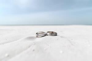 Two wedding rings in the sand on the background of a beach and sea. photo