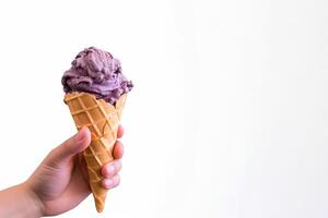 Hand holding delicious blueberry ice cream in a crispy waffle cone with copy space. photo