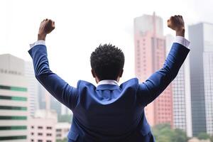 Successful businessman raising hand and expressing positivity while standing against skyscrapers background. photo