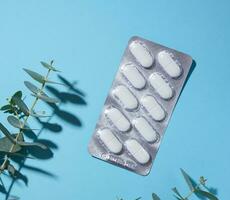 Oval white pills in a gray blister pack on a blue background photo