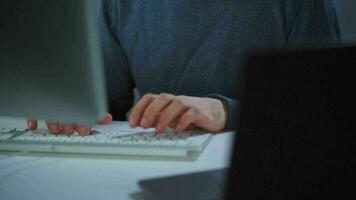 Male hacker in the hood and glasses working on a computer in a dark office room. Cybercrime concept video