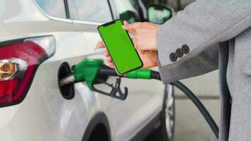 mujer usos un móvil solicitud en un teléfono inteligente a pagar para repostaje un coche. teléfono inteligente con un verde pantalla. croma llave video