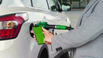 mujer usos un móvil solicitud en un teléfono inteligente a pagar para repostaje un coche. teléfono inteligente con un verde pantalla. croma llave video