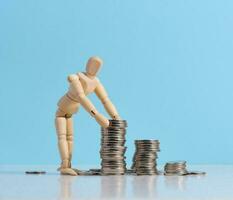 Wooden dummy and stacks of white coins, the concept of accumulation of cash, donation, subsidy photo