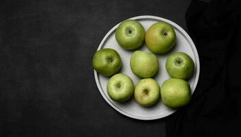 maduro verde manzanas en un gris lámina, parte superior ver en un negro de madera mesa foto