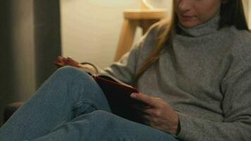 mujer acostado en el sofá en un acogedor habitación y leyendo libro en el noche video