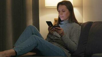 Woman lying on the sofa in a cozy room and makes an online purchase using a credit card and smartphone. Online shopping, lifestyle technology video