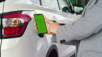 mujer usos un móvil solicitud en un teléfono inteligente a pagar para repostaje un coche. teléfono inteligente con un verde pantalla. croma llave video