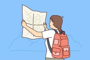 Woman tourist looks at map choosing route for trip through wild during hike in mountainous area. Girl tourist with backpack behind back studies map of national park and enjoys journey vector