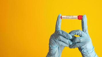 hand- houden ommicron variant corona virus bloed test buis Aan geel achtergrond video