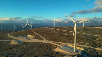 Windmühlen auf den Hügeln bei Sonnenuntergang. erneuerbare energie, grüne energie. Berge im Hintergrund mit Schnee. Windkraft und umweltfreundlich. nachhaltige Zukunft. Schluss mit fossilen Brennstoffen. video