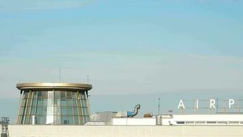 Long shot of an unrecognizable aircraft taking off, climbing. Control tower foreground. Airport. Tourism and travel concept video