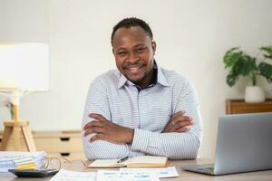 African American businessman smiling relaxed and crossed arms after analysis and research at home office photo