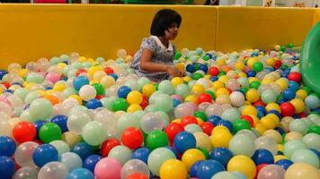 vista superior da menina criança brincando com muitas bolas de plástico coloridas video